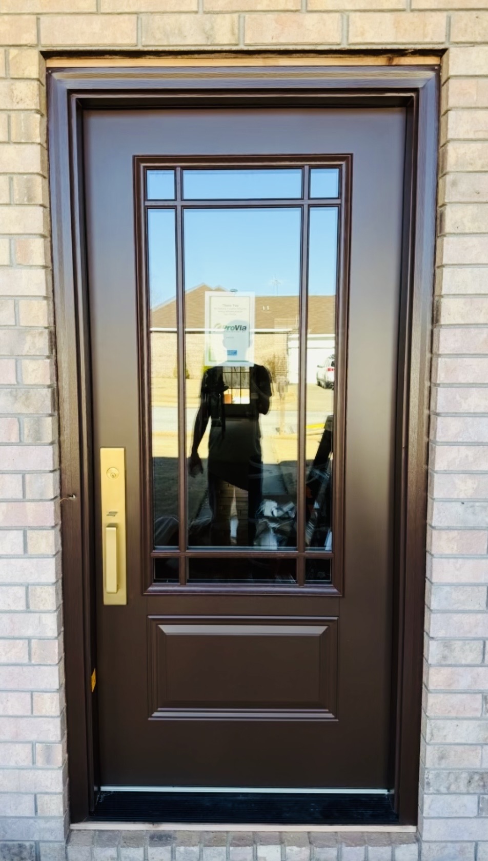 Finished dark brown entry door with glass panel after installation